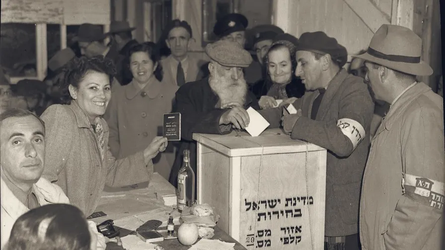 A voter drops his envelope into the ballot box at a polling station on election day, 25 January 1949.